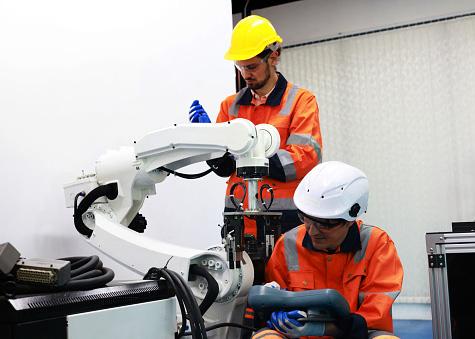 Colleagues Mechanical Engineers test programs and simulation robots arm in industrial laboratories.