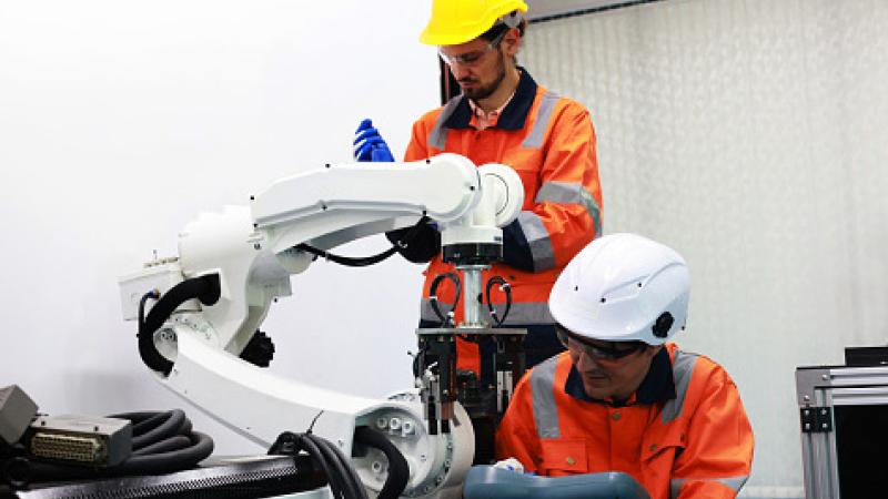 Colleagues Mechanical Engineers test programs and simulation robots arm in industrial laboratories.
